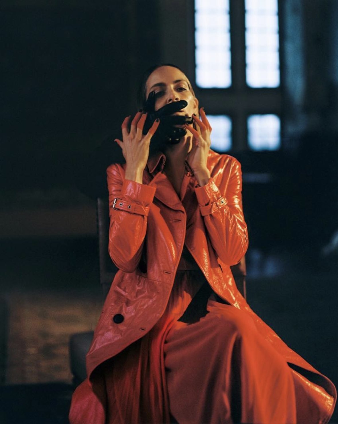 Fashion editorial, red patent trench coat in low light