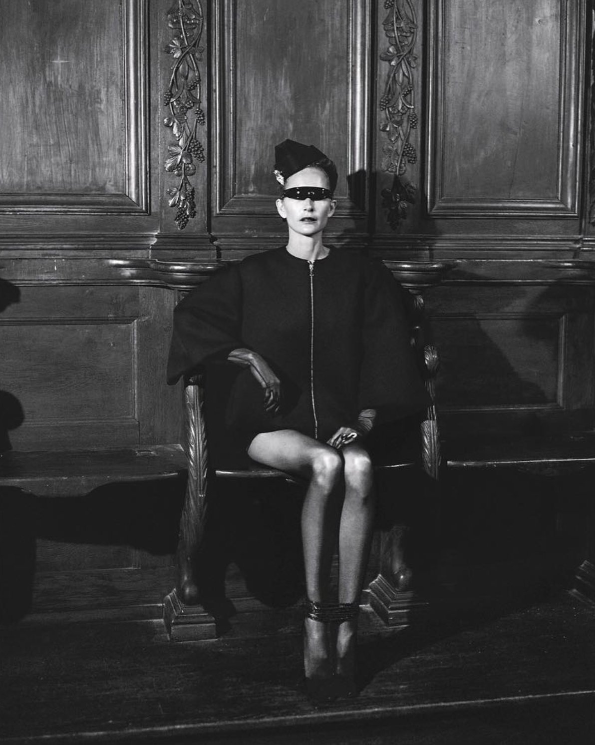 Black and white fashion editorial, seated portrait in a panelled interior